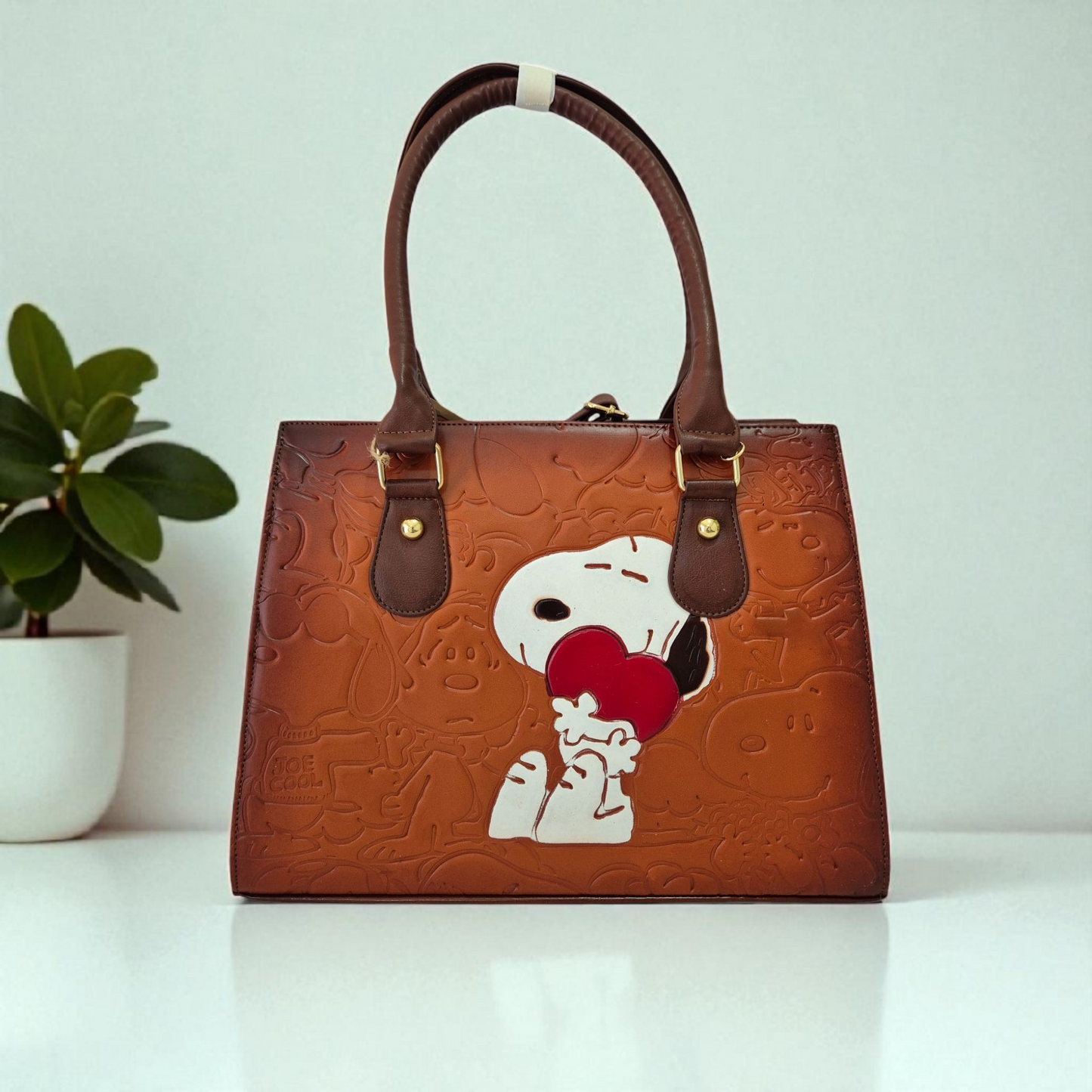 Bolsa artesanal de piel café con diseño grabado de personaje abrazando a un corazón rojo